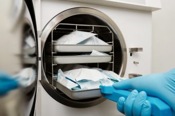 young male dentist places medical autoclave sterilising surgical other instruments